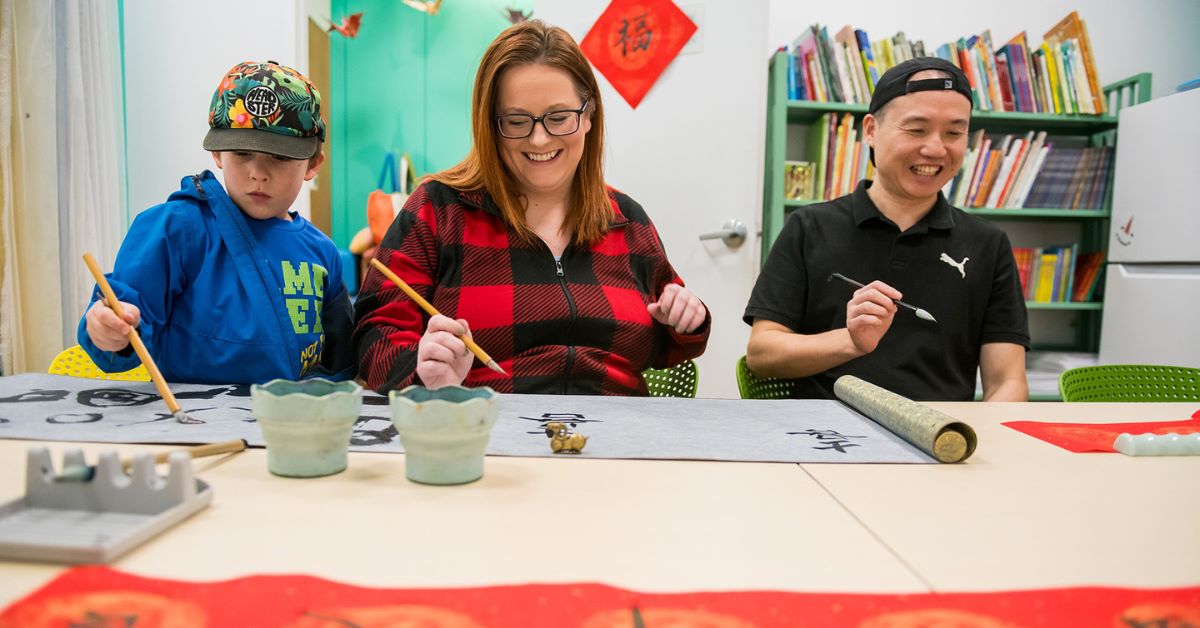 Three people painting together at a table, enjoying a creative activity.