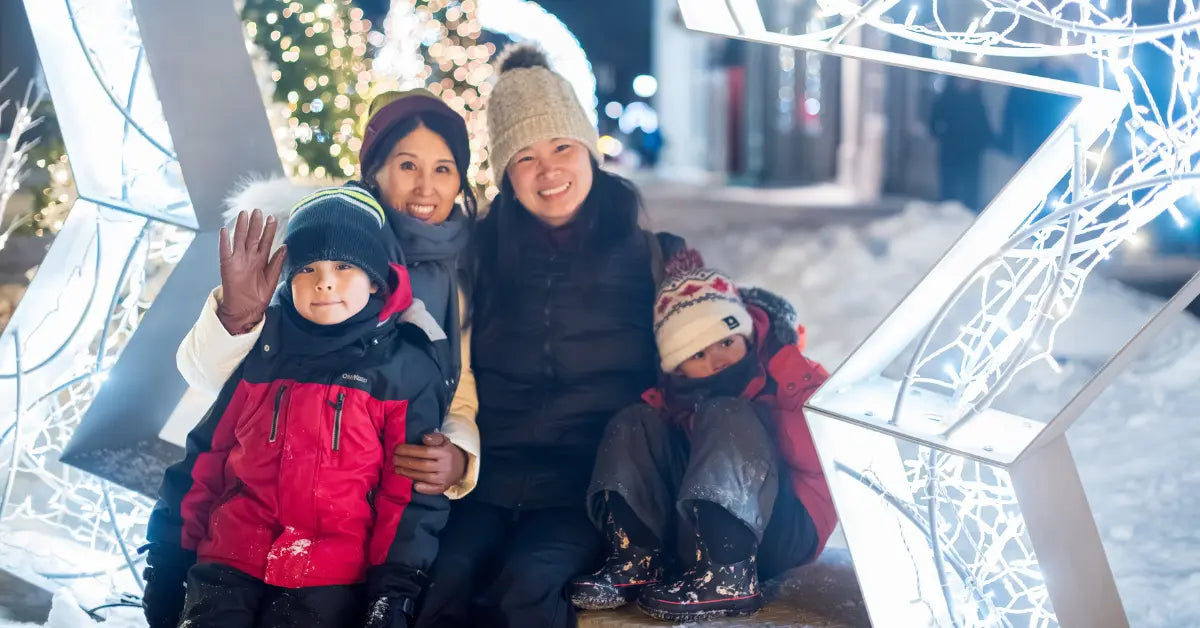 A family poses happily with winter lights in the background.
