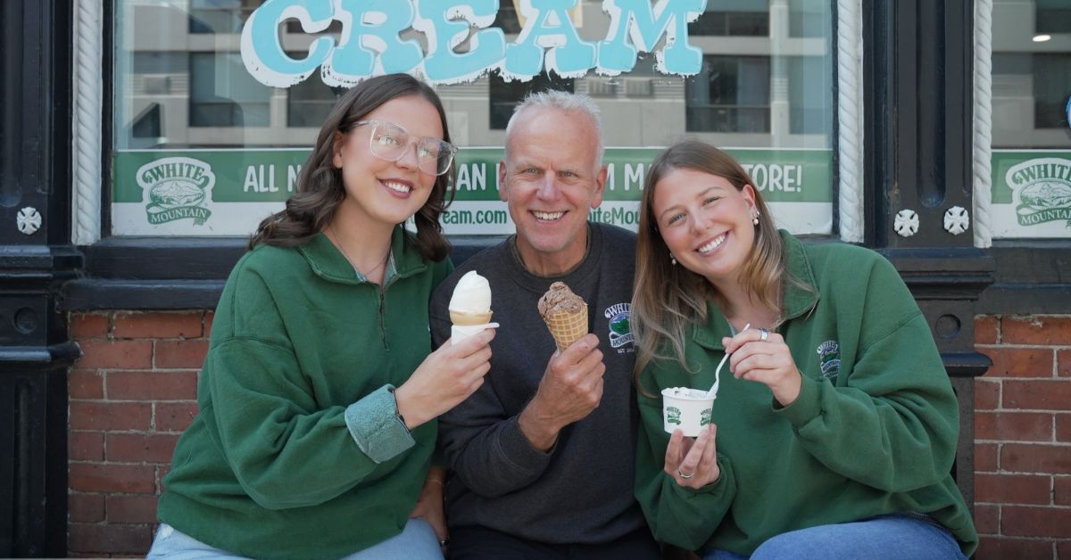 Three people enjoying ice cream in front of a shop.