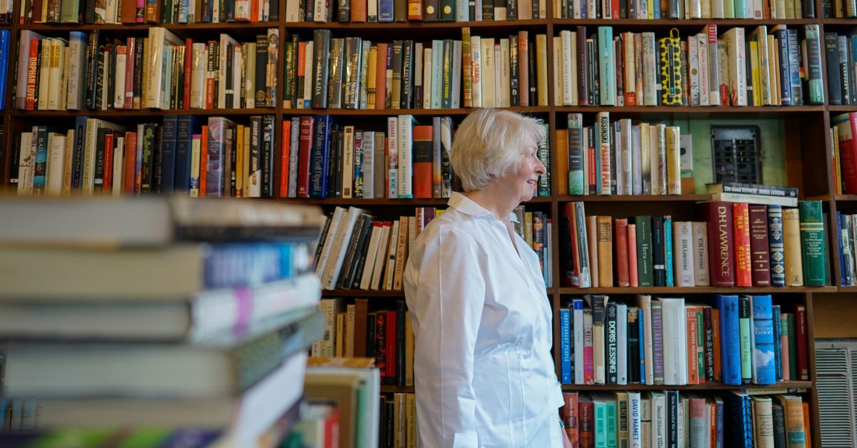 Jan Walter standing near a large bookshelf filled with books at Berry Peterson Bookestore.