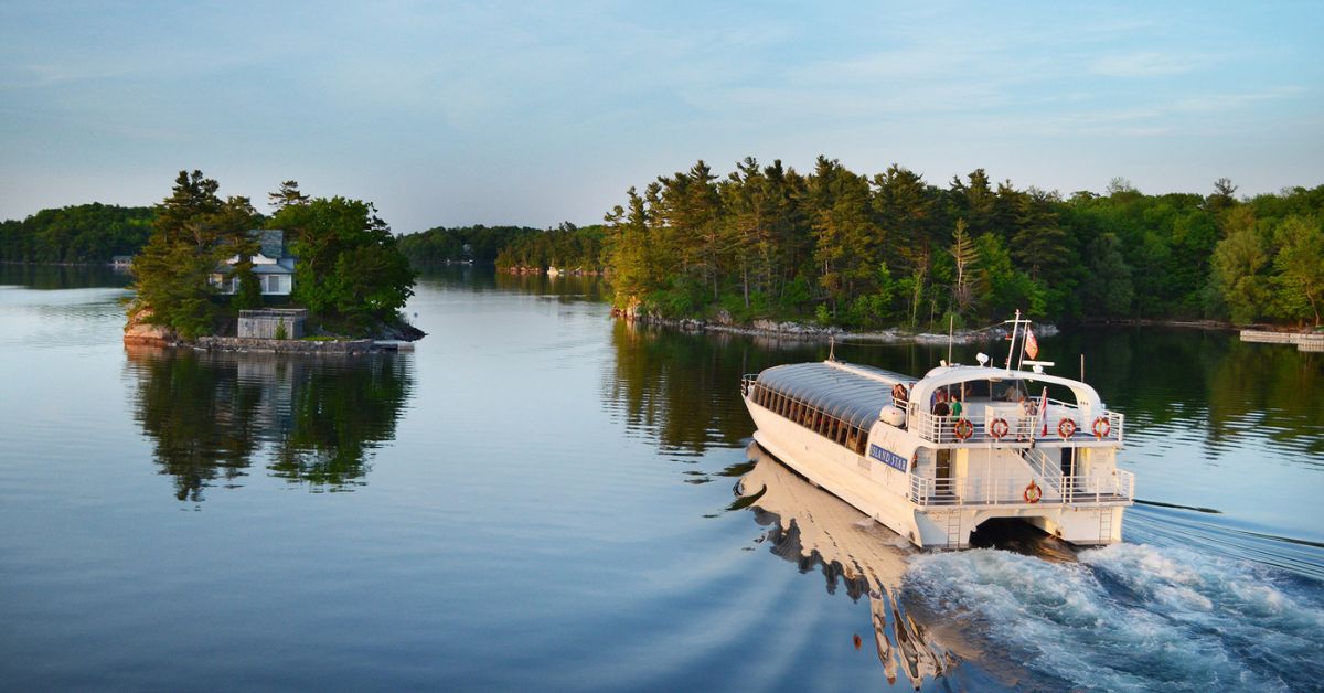 A boat navigating through a calm lake surrounded by trees and islands.
