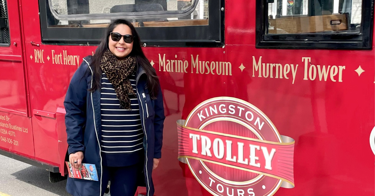 Person standing next to a red trolley with "Kingston Trolley" sign.