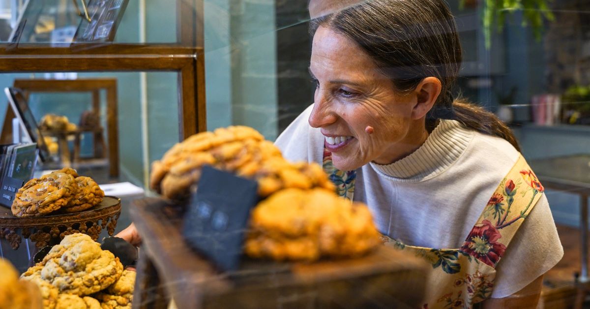 Woman admiring freshly baked cookies in a bakery display.