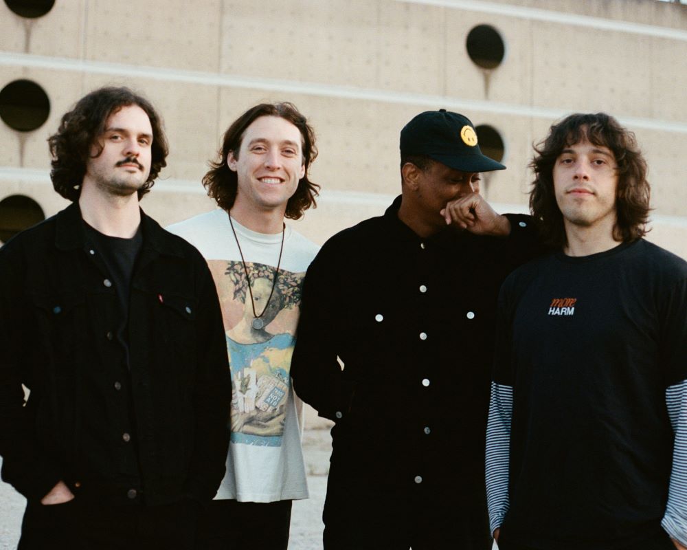 Four men who make up the band Kasador are standing together in front of a building