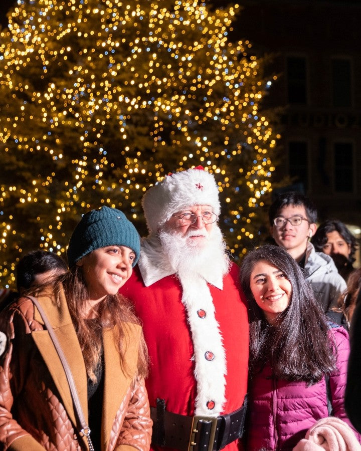 People posing with Santa Claus in front of a Christmas tree.