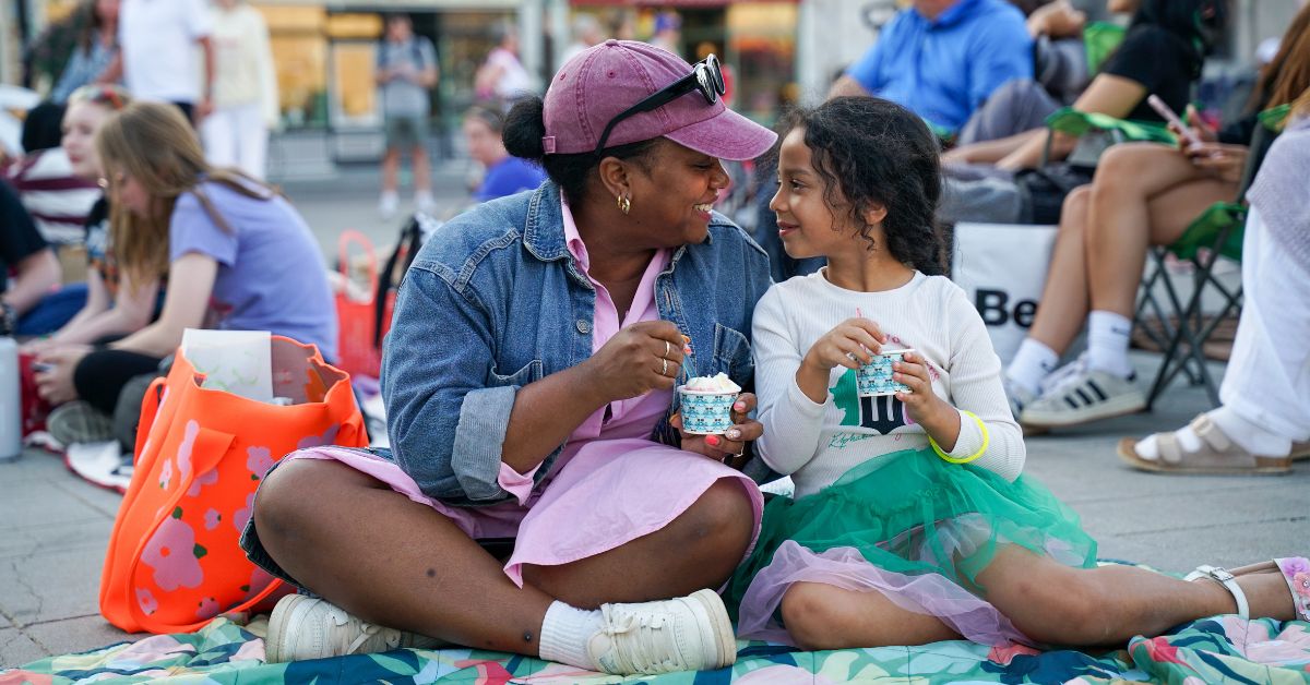 Two people enjoying ice cream while sitting on a blanket.