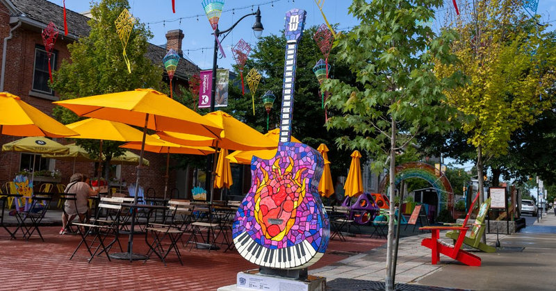 Colorful guitar sculpture in a lively outdoor dining area with yellow umbrellas.