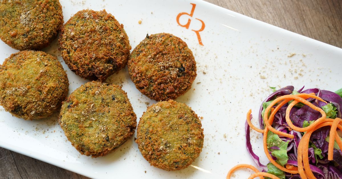 Plate of crispy falafel balls with colorful salad on the side from Daal Roti.