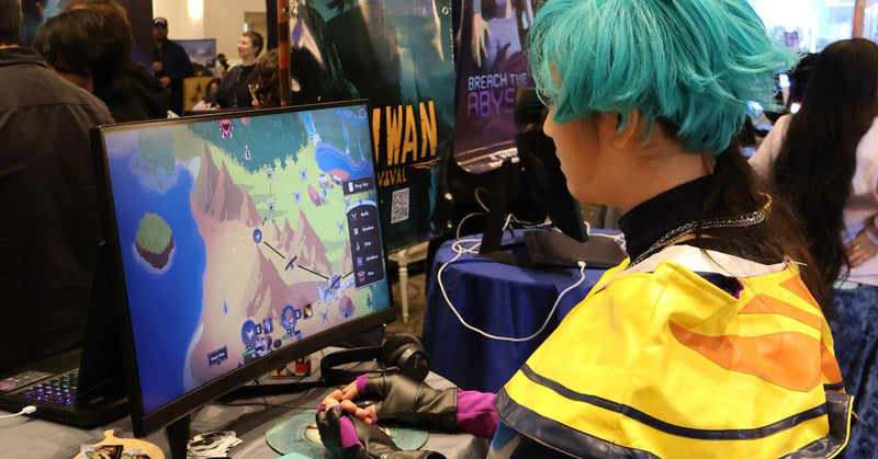 Person with blue hair playing a video game at an event.