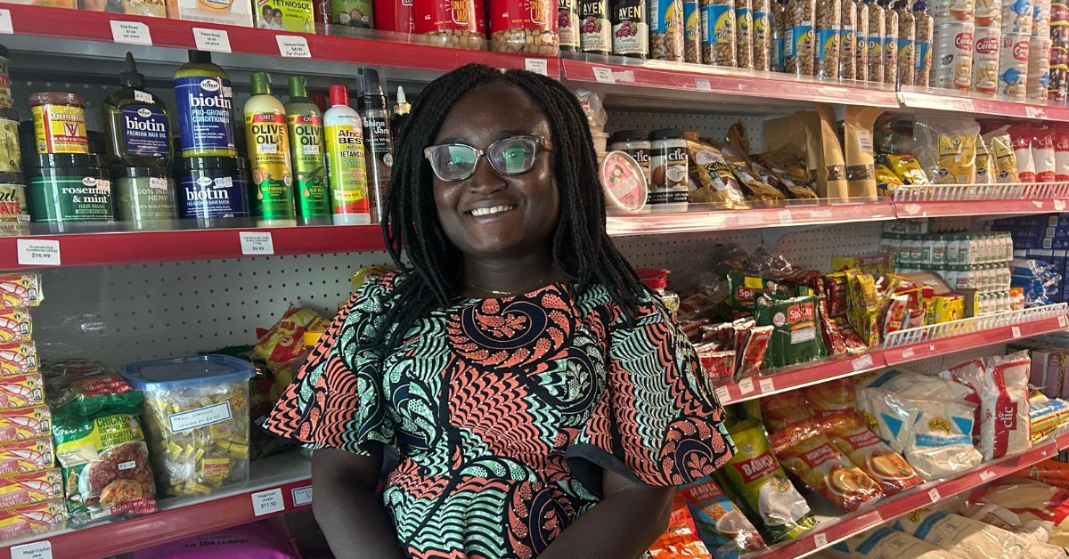 Smiling woman in colorful dress standing in a grocery store aisle.