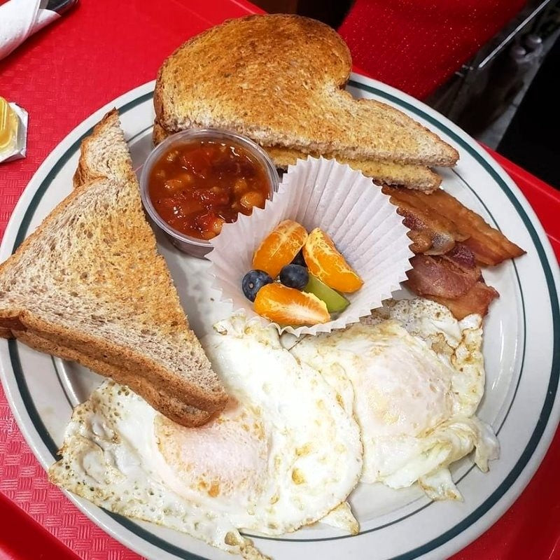 A breakfast plate with toast, fried eggs, bacon, beans, and fruit from Chit Chat Cafe, located in downtown Kingston, Ontario.