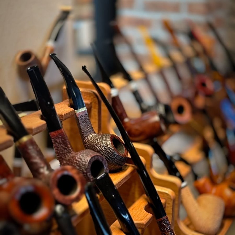 Collection of pipes displayed on a wooden rack with a blurred background