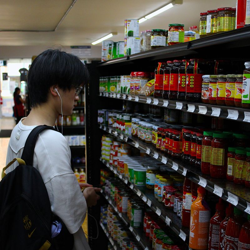 Person shopping in a supermarket aisle with various products on shelves.