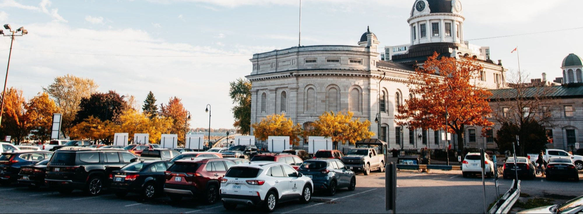 Kingston City Hall in downtown Kingston Ontario with fall colors, parked cars, and a clear blue sky
