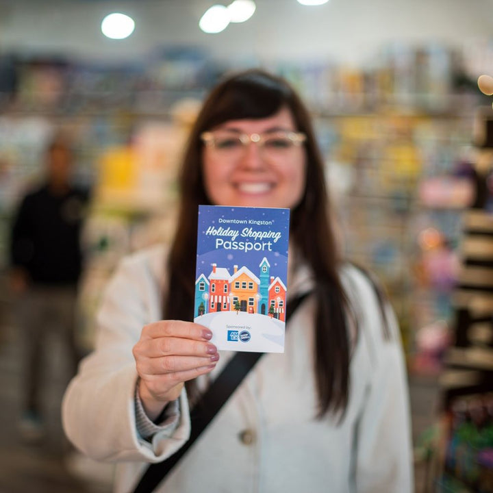 Woman holding a 'Holiday Shopping Passport' in a store setting
